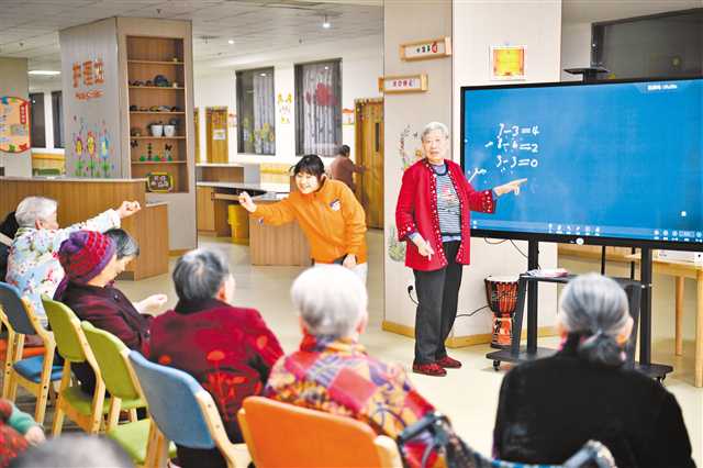 一月十七日，巴南區(qū)花溪街道社區(qū)養(yǎng)老服務(wù)中心認(rèn)知障礙照護(hù)專區(qū)，曾是數(shù)學(xué)老師的龐素清（右二）在志愿者的帶領(lǐng)下與老人們一同做算術(shù)題。記者 謝智強(qiáng) 實(shí)習(xí)生 康海雨 攝\視覺重慶