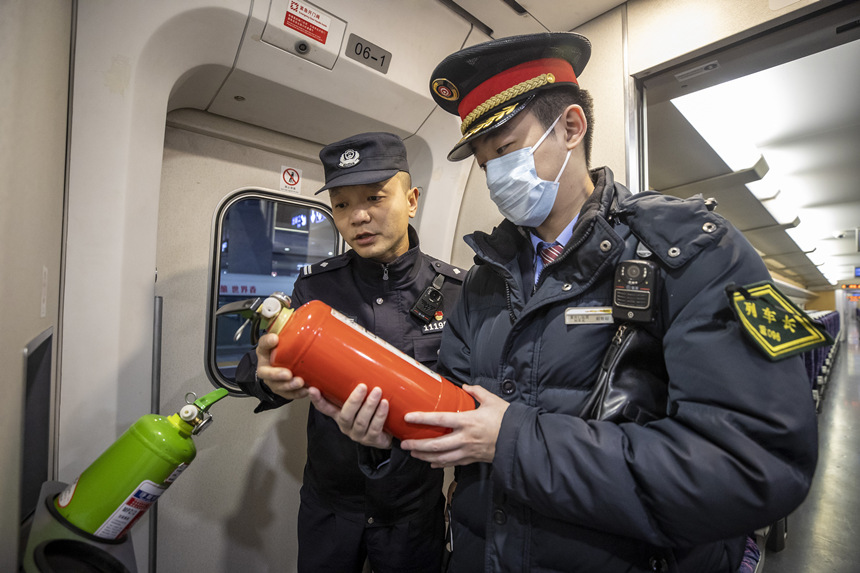 彭聰（左一）在列車長的配合下，對列車配備的滅火器進(jìn)行檢查。胡勇攝