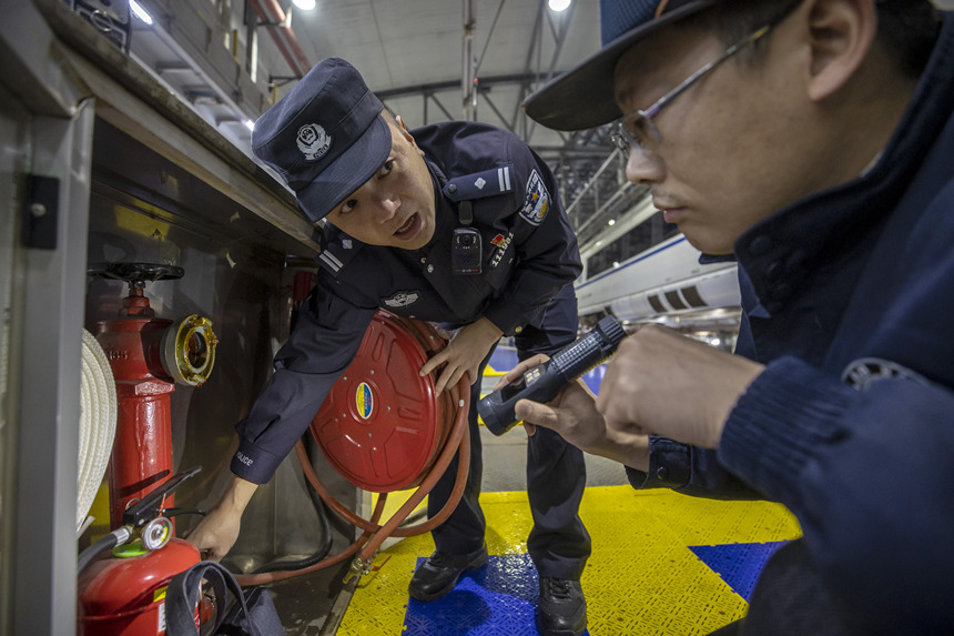 彭聰（左一）在重慶北動(dòng)車所工作人員的配合下，對檢修庫的消防栓進(jìn)行檢查。胡勇攝