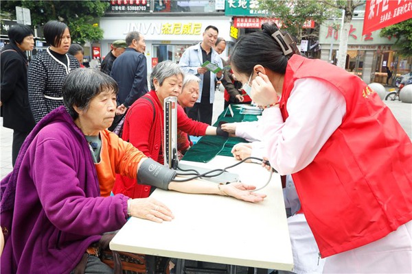 “梁家人”利民醫(yī)院志愿服務(wù)隊(duì)隊(duì)員為市民測量血壓。譚燕攝