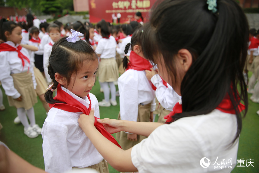 高年級(jí)學(xué)生為新入隊(duì)的少先隊(duì)員佩戴紅領(lǐng)巾。人民網(wǎng)記者 劉政寧攝