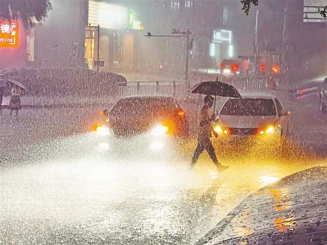 7月13日晚，渝北區(qū)獅子坪輕軌站，市民撐傘在暴雨中走過。當(dāng)晚，主城區(qū)出現(xiàn)雷電暴雨天氣。記者 劉力 攝/視覺重慶