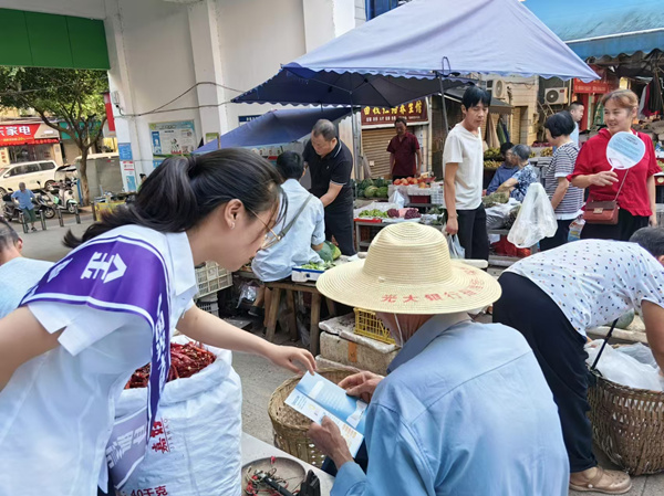 志愿者走訪農(nóng)村集市的各個攤位，進(jìn)行流動宣傳。光大銀行重慶分行供圖